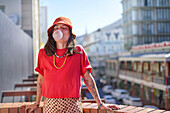 Young woman blowing bubble gum bubble on rooftop