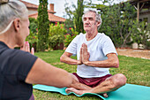 Serene senior couple meditating in summer garden