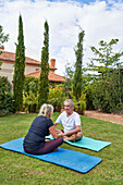 Senior couple holding hands and talking on yoga mats