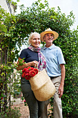 Senior couple with flowers walking under trellis in garden