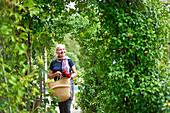 Senior woman walking under trellis in summer garden