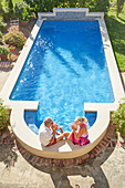 Senior couple drinking cocktails by swimming pool