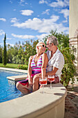 Senior couple talking by swimming pool