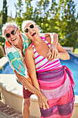 Senior couple hugging at sunny poolside