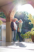Senior couple talking in sunny villa archway
