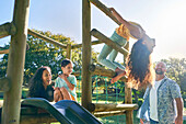 Family playing on playground equipment in sunny backyard