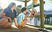 Family playing at playground structure in sunny park