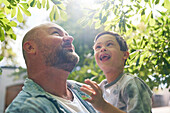 Father and son with Down syndrome below tree