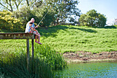 Father and son fishing on sunny lakeside dock