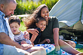 Family hugging outside tent at summer campsite