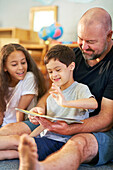 Boy with Down syndrome reading book with family at home