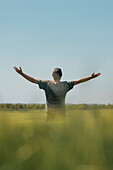 Man raising hands in field