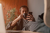 Man using smartphone and drinking coffee