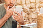 Man using smartphone with laptop