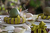 Easter egg in a nest decorated with feathers and eggshells on a garden table
