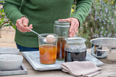 Woman dyeing Easter eggs, different colors in jars