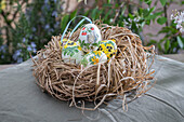 Easter nest made of straw with self-painted Easter eggs with flower decoration