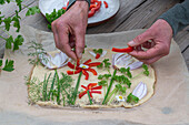Garnishing flatbreads, decorating raw dough with fresh herbs, onion strips and blossom made from pepper strips before baking