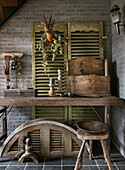 Rustic table, wooden box and shutters with louvres in front of brick wall