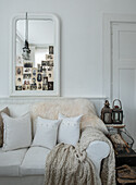 White couch with cushions, fur, blanket and collage of vintage photos in bright living room