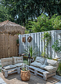 Seating area in the garden with pallet furniture and privacy screen