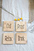 Wooden coasters with engravings Chill", "Cheers", "Relax", "Drink" on linen cloth"