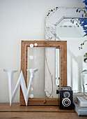 Decorative still life with vintage camera and wooden frame on chest of drawers