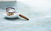 Small sieve with icing sugar on a plate