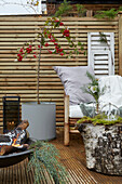 Terrasse mit Sichtschutz aus Holz, mit Bambusstuhl, Feuerschale, Topfpflanze und Dekoration