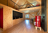 Moderne Küche mit Holzverkleidung, roter Kaminofen und offener Galerie