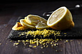 Geschnittene Zitrone, abgeriebene Zitronenschale auf dunklem Hintergrund