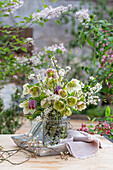 Blumenstrauß aus Felsenbirne (Amelanchier), Schachbrettblume (Fritillaria meleagris), Schlehe, Lenzrose (Helleborus orientalis) in Vase auf Terrassentisch