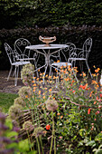 White metal garden furniture set with ornate decorations in the flowering garden