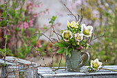 Lenzrose Hybride 'White Spotted Lady' (Helleborus Orientalis), kleiner Strauß in Vase auf Gartentisch