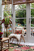 Rattan chair with embroidered cushion and sheepskin in the conservatory