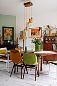 Retro-style dining room with colourful chairs and various works of art