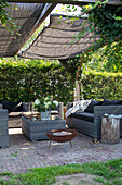 Cosy seating area in the garden with rattan furniture, sunshade and fire pit