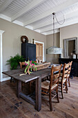 Dining room with rustic table, wooden chairs and grey pendant lamp