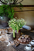 Rustikaler Holztisch mit Wildblumenstrauß und Schokoladenstücken auf Holzbrett