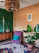 Sitting area in the living room with purple armchair, rug and houseplants