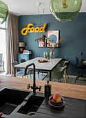 Dining area with blue-green wall paint, industrial lights and neon-colored Food lettering