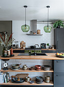 Modern kitchen with wooden shelves, glass pendant lights and green accents