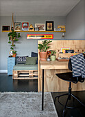 Work area made of light-colored wood, sofa made of pallets in the background