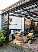 Covered terrace with lounge sofa, rattan chair and wooden table