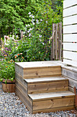 Holztreppe vor blühenden Stauden im Garten