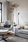 Cozy sitting area with light grey armchair, sofa and dried flower decoration