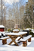 Snow-covered rustic wooden table in winter garden