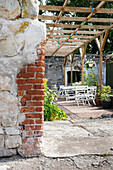 Pergola with colourful fairy lights and white garden furniture in the backyard