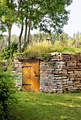 Natural stone wall with wooden door and grass roof in the garden