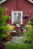 Romantische Gartenecke mit Sitzbereich vor roter Holzwand